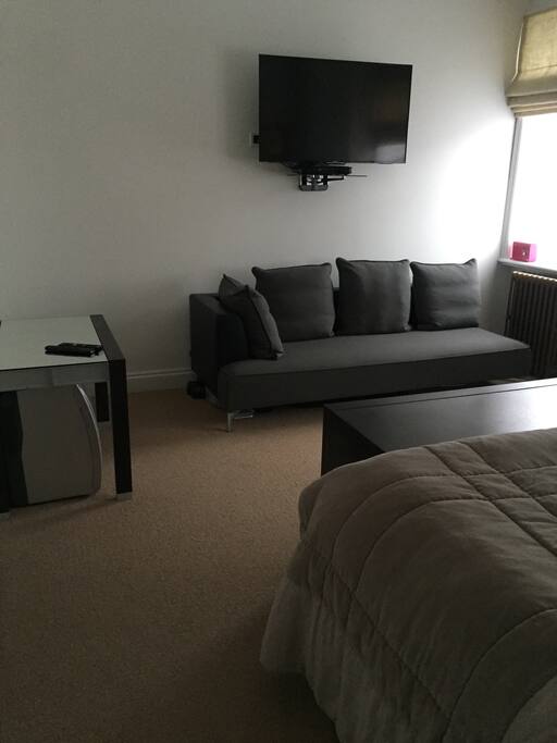 Spacious bedroom with sofa, television and dressing table