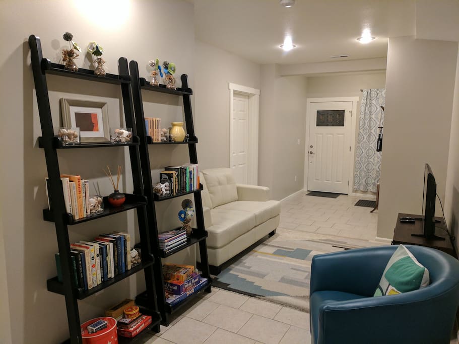 Living area includes a couch, swivel chairs, TV, and bookshelves. We've provided reading materials and games for nights in. Ottomans can be moved around the unit for extra seating as needed.
