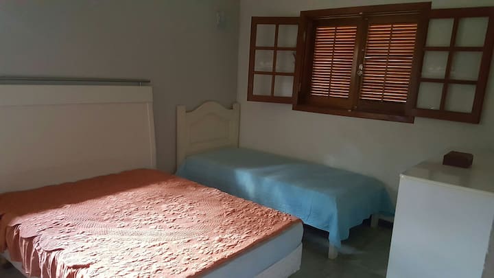 Apartmán, manželská posteľ a jednolôžko, na podlahe je miesto pre ešte jeden matrac.