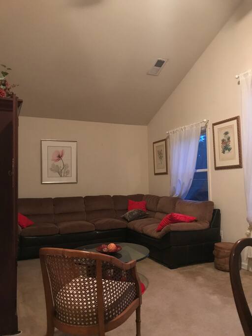 Living room area with cathedral ceiling, large mahogany desk, ceiling fan with light and programmable controls, large windows and closets, double sofa, coffee table, wall to wall carpet, and WIFI.