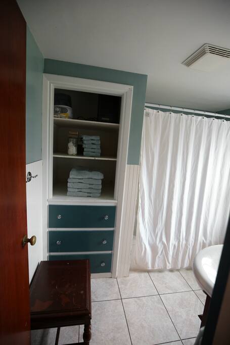 Full bathroom with shower, tub, sink, linen shelves, and toilet.