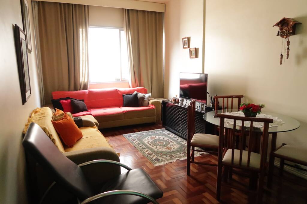 Sala de estar compartilhada com televisão, sofás e mesa de jantar