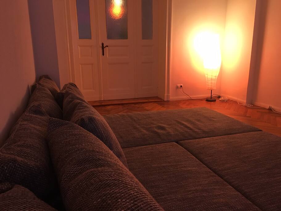 The couch in the cozy living room has a lot of space to comfortably watch movies.