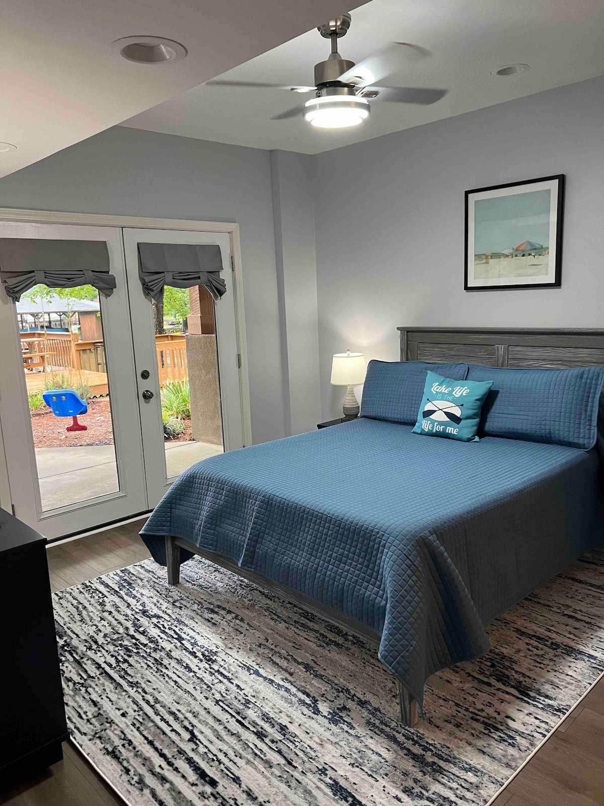 5. spálňa s 1/2 kúpeľňou a manželskou posteľou.  K dispozícii je televízor YouTube a stropný ventilátor. Pohľad na jazero a prístup na terasu a dvor cez francúzske dvere.