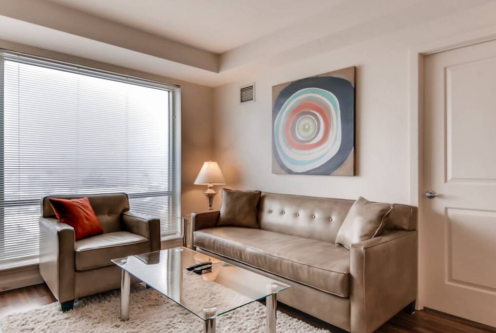 Comfortable living room with pullout sofa bed, club chair and floor to ceiling windows providing lovely natural light and views