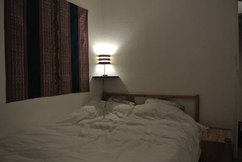 Un lit double confortable ac table de nuit et lampe de chevet
