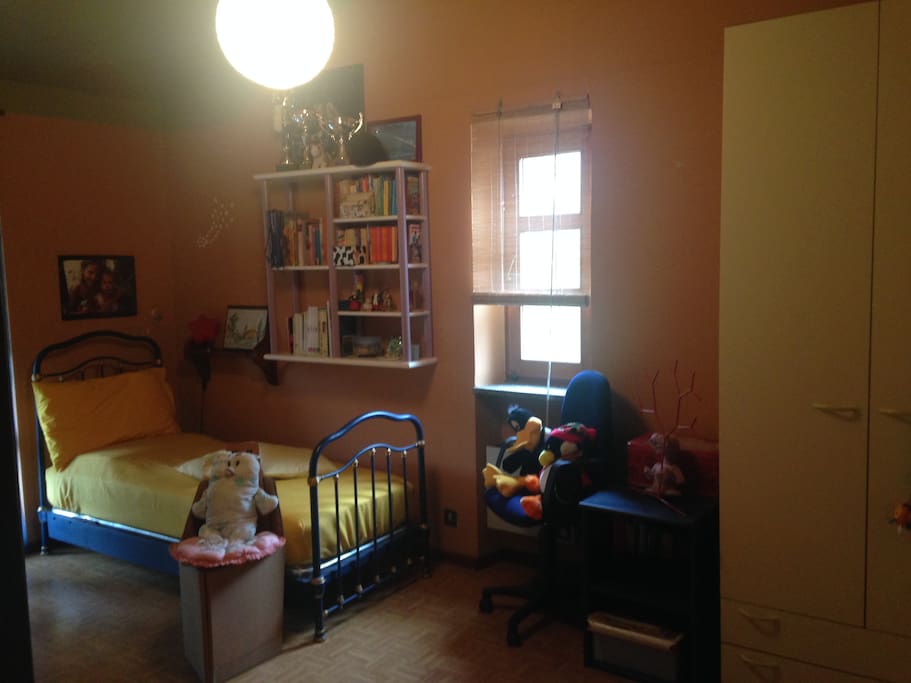 Camera da letto con due letti, un grosso armadio ad angolo, due scrivanie, due sedie, librerie e balcone che da sul giardino - 1° piano