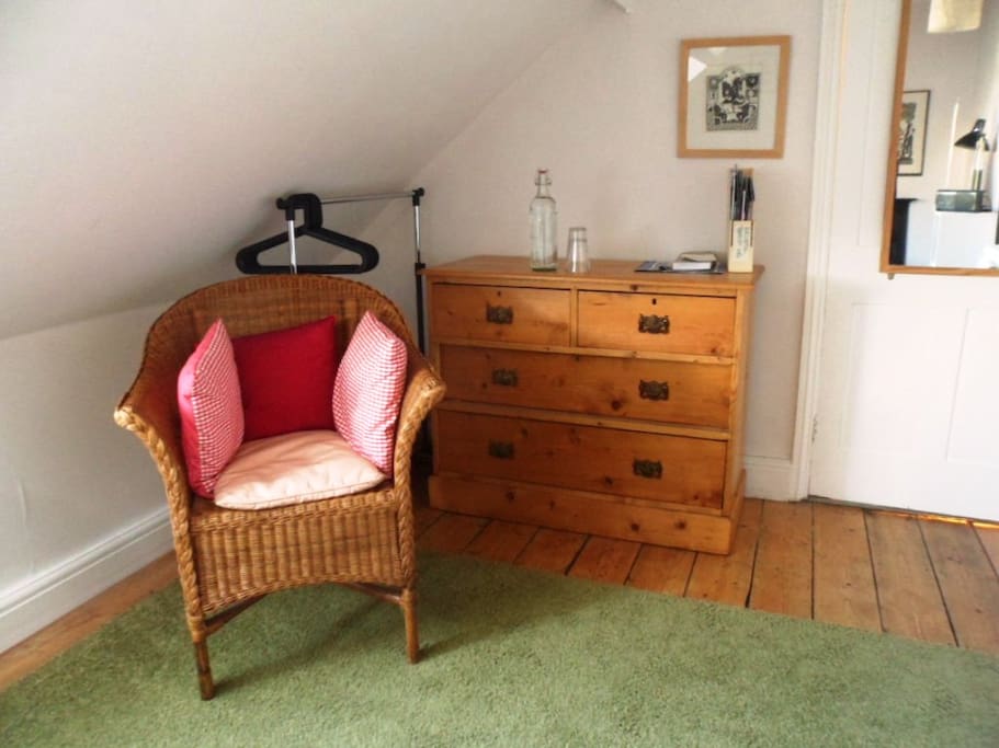 Close up of seat and chest of drawers and clothes hanger.