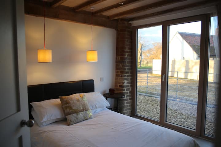 Двоен кревет со втора спална соба, гардероба и отворена врата кон поплочениот двор. 