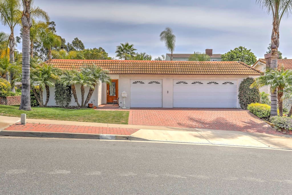 Approach the home’s entrance from the nicely landscaped front yard with mature, swaying palm trees.