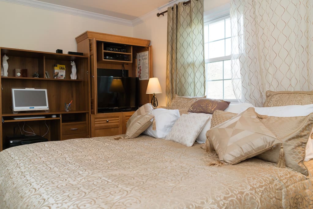 Bedroom has flat-screen TV and large window behind bed.