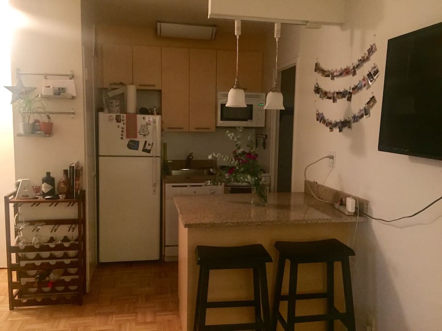 Kitchen with fridge, stove, dishwasher, microwave, bar style counter top table, and mini bar.
