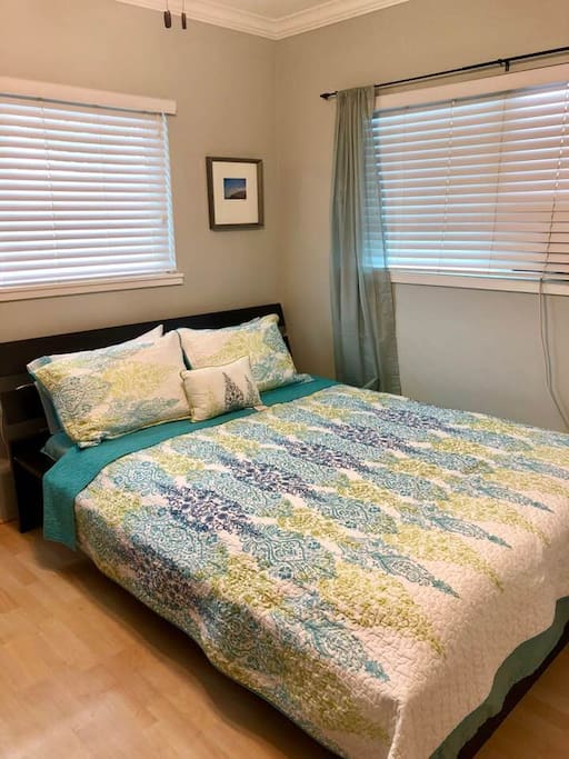Cozy guest bedroom with an air conditioner, ceiling fan and desk.