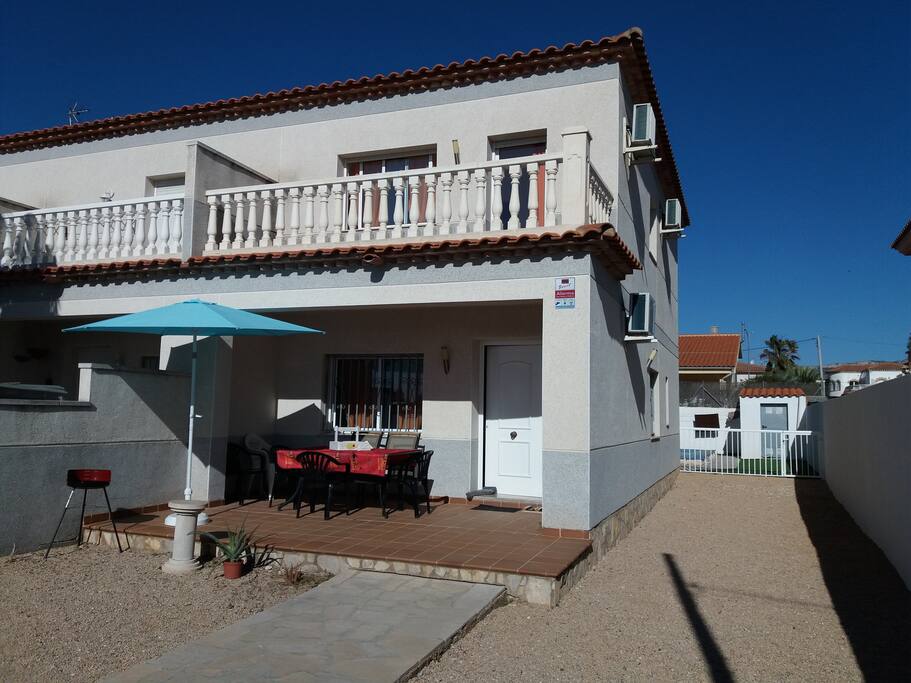 Vue de face de la maison avec passage latéral sur le côté donnant accès à la piscine privée.