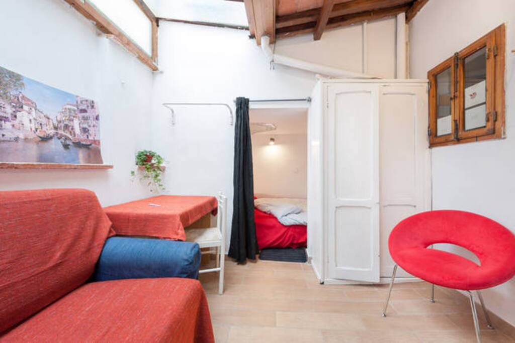 Tranquilla camera luminosa con letto matrimoniale, studio interno con scrivania e divano e bagno privato.
