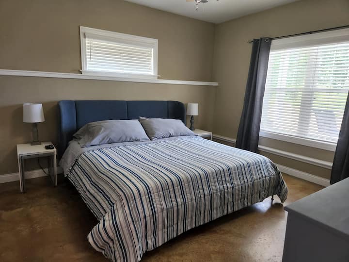 Downstairs bedroom with king bed, dresser, and TV.