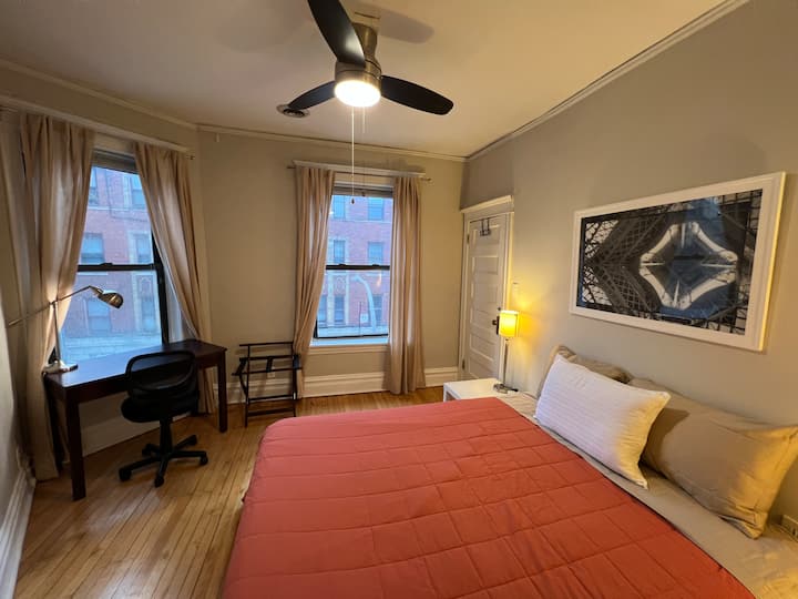 Première chambre lumineuse avec un bureau et un lit queen size