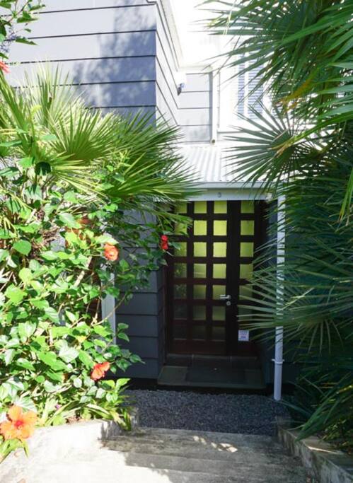 Welcome to Garden House - walk down through palms and hibiscus flowers to the front door.