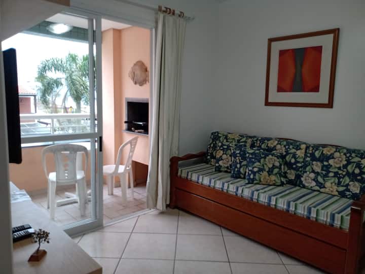 Salon avec canapé-lit et balcon avec barbecue.