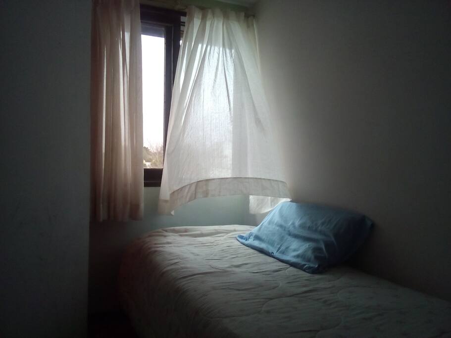 Habitación chica con una cama simple.