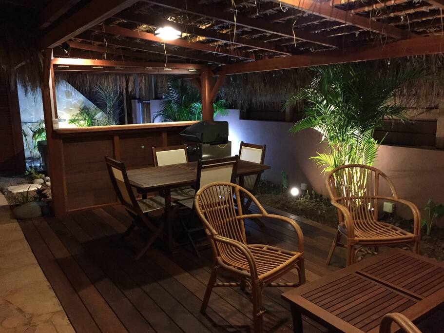 Terrasse extérieure en bois exotique et couverture feuille de palme. Bar donnant sur espace Jacuzzi