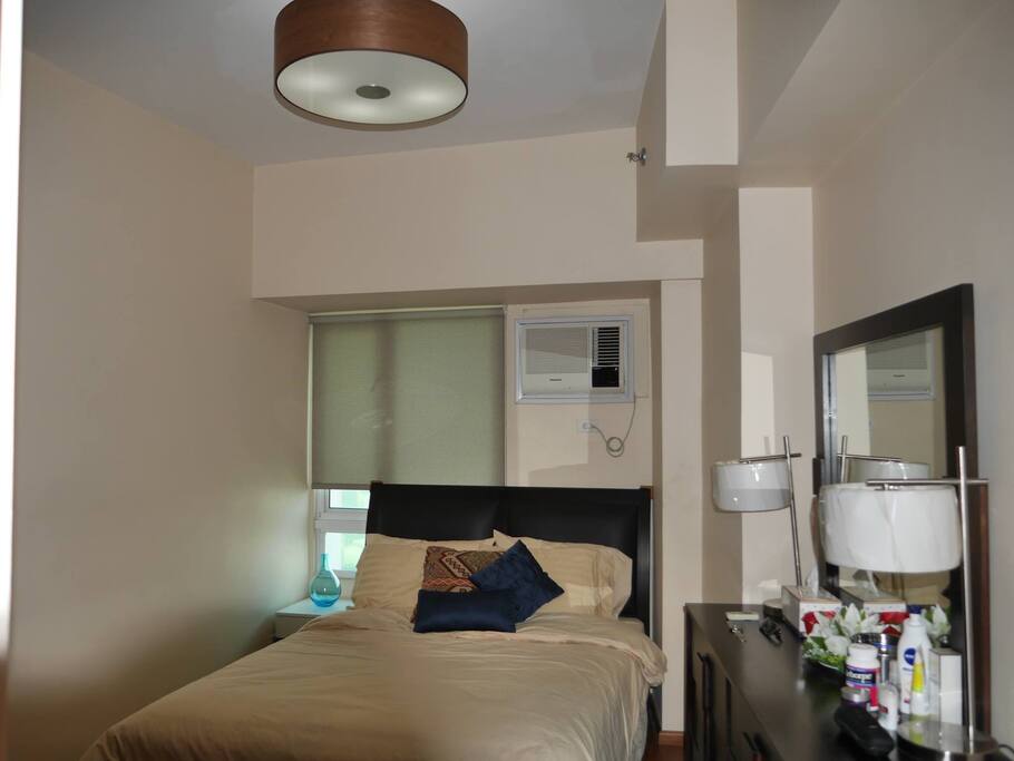 Spacious bedroom with private bathroom, dresser, big closets and air conditioning unit.