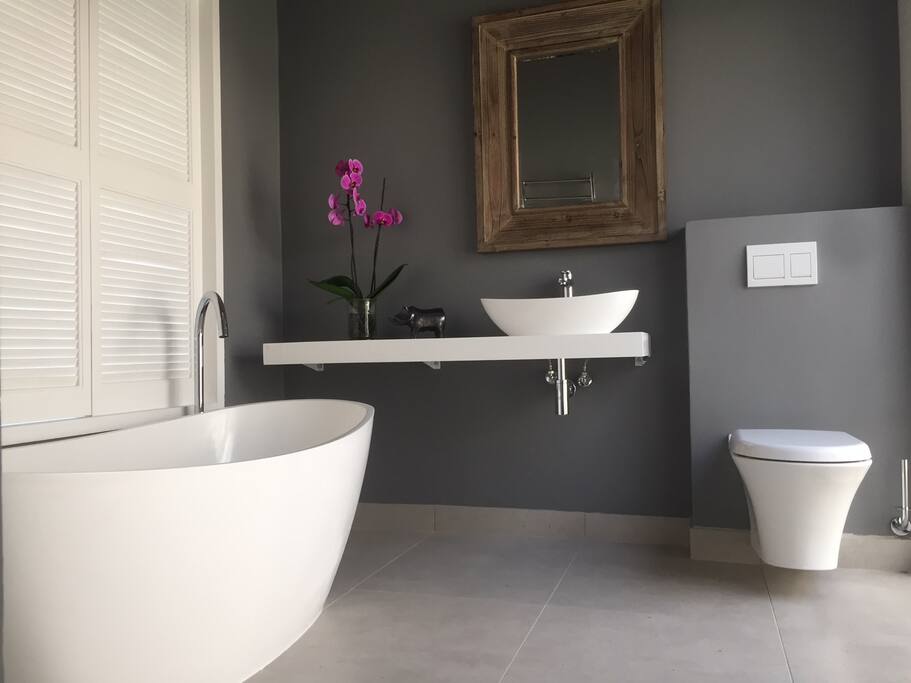 Luxurious bathroom with shutters that open to bedroom