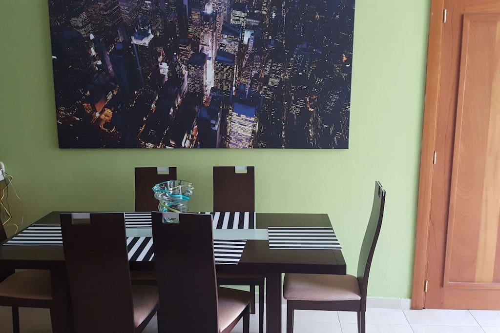 Dining area with modern table with portrait of a bird's eye view of NYC night sky.