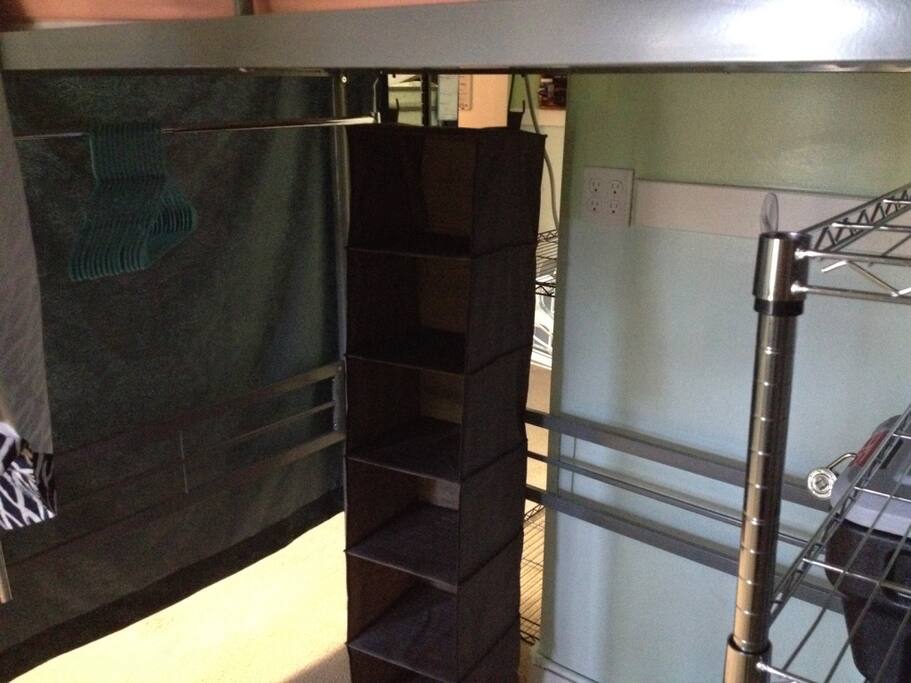 Storage for loft bed (under loft bed shown in previous picture). Includes clothes hanging rack, cloth shelves and metal wire shelves. Metal wire shelves have lockable black bin and storage bin available.