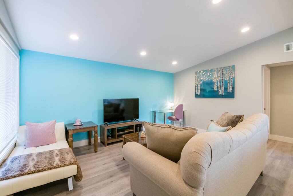 The living room has a smart TV (with Netflix subscription), 5G Wifi (through the whole house), a set of working desk/chair, and a lounge bed.