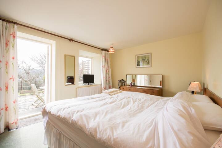 Master bedroom with access to patio and garden. Open the door and listen to the sea. 
