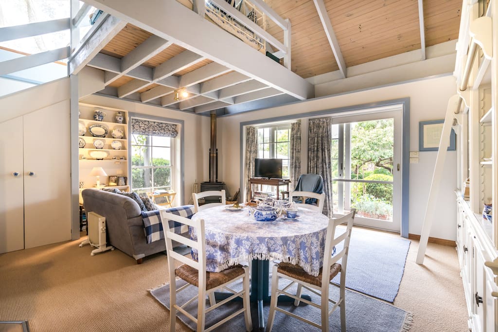 Light filled open plan lounge , with wood heater , dining , kitchenette , facing north .