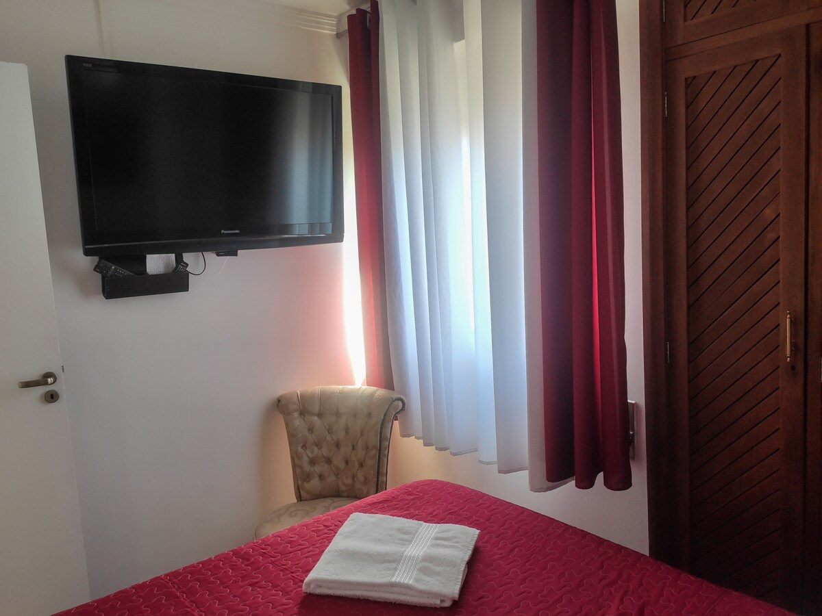 Habitación con una cama doble y un televisor, accediendo a canales abiertos. 