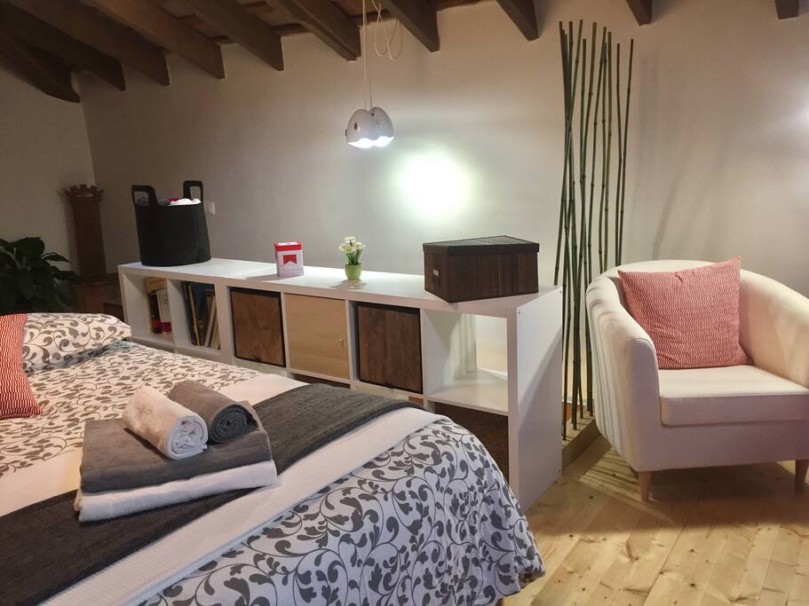 Un acogedor dormitorio con cama de matrimonio, y una zona de lectura.