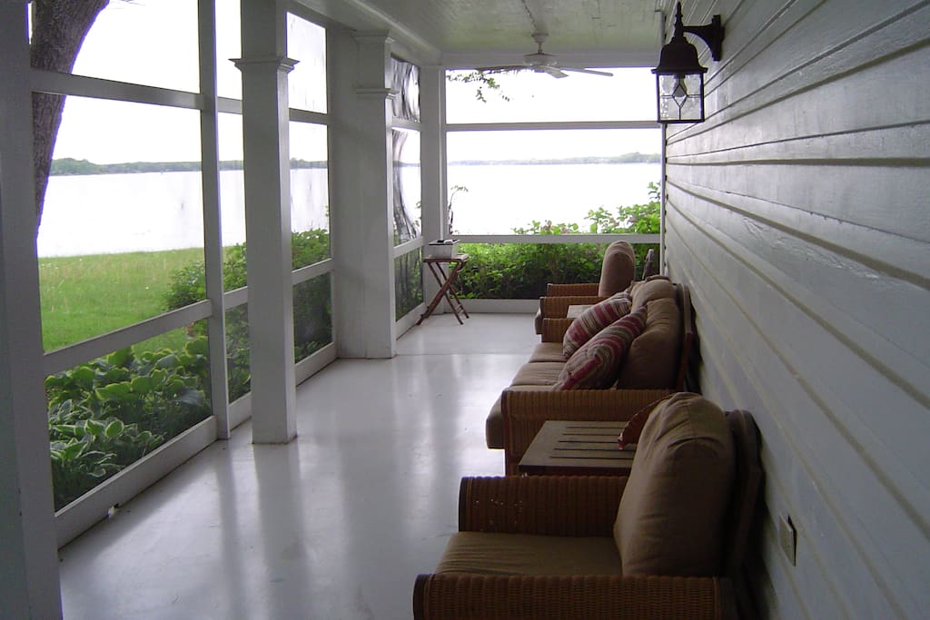 Enjoy comfortable moments on the L-shaped screened porch, with large comfortable chairs and sofa and table for outdoor dining.