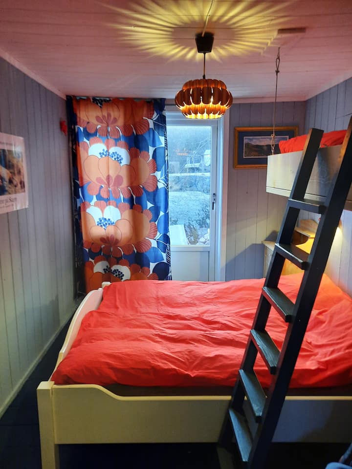 O quarto no primeiro andar tem uma cama de casal (150 cm) e uma cama de solteiro de altura. Há uma porta diretamente para o terraço.