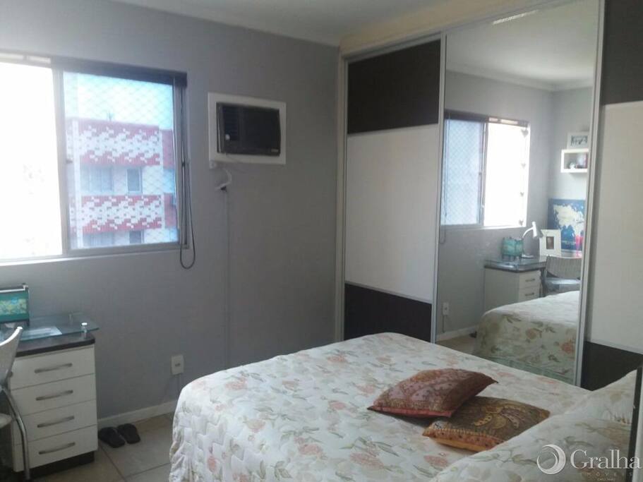 Com um amplo guarda roupa com espelho, ar condicionado e escrivaninha