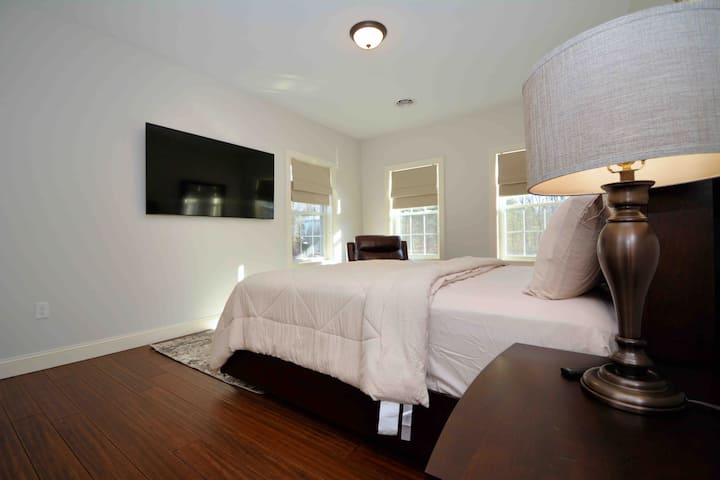 تحتوي غرفة النوم 8 من 9 على سرير بحجم كبير آخر، وتلفزيون سامسونج الذكي 65 بوصة، وكرسي تدليك، وخزانة ملابس، وأكشاك ليلية، ومصابيح.