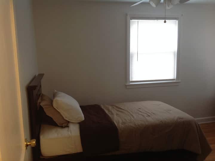 Mala spavaća soba s dva odvojena kreveta i dva ormarića.