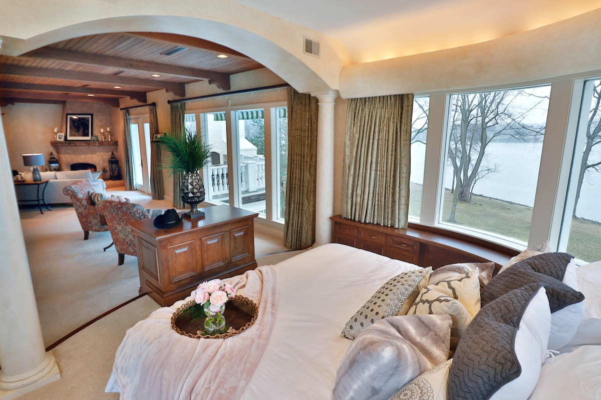 Spavaća soba 1 - Prekrasan glavni apartman ima privatni dnevni boravak, kamin, bračni krevet i pristup balkonu. Prozori od poda do stropa u glavnoj spavaćoj sobi omogućuju prirodno svjetlo da poplavi prostor i pruža izvrstan pogled na jezero. 