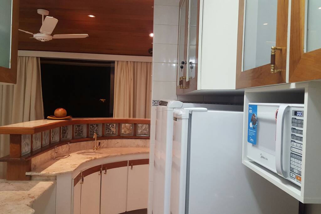 Cozinha com geladeira, freezer, microondas, fogão e utensílios
