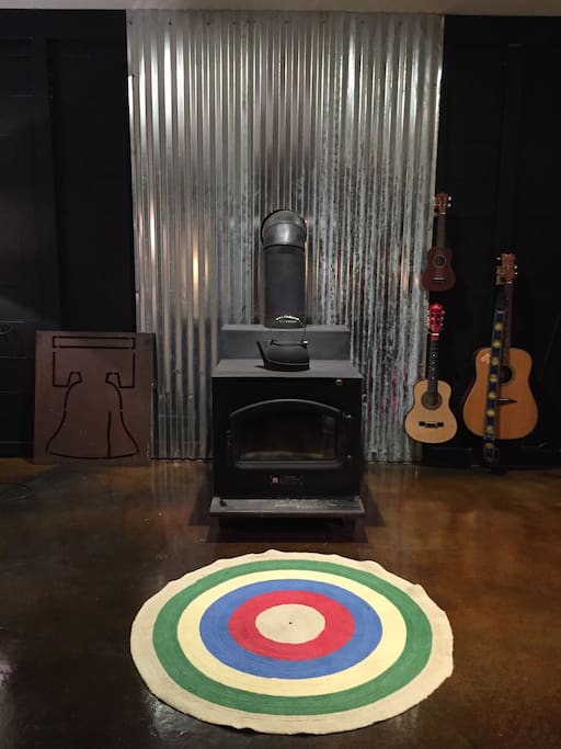 Wood burning stove in the open floor plan living room is ready to keep you toasty on chilly nights. Notice the custom stained concrete floors. They run throughout the common areas of the house. Feel free to play the guitars or the ukulele. :)