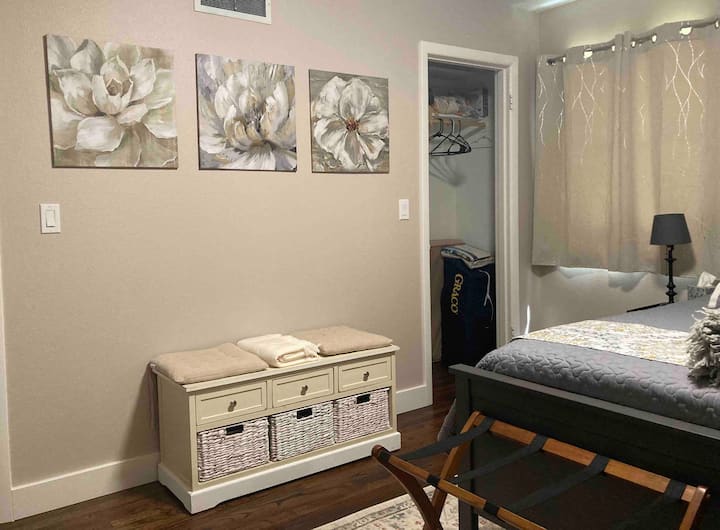 Sitting bench with view of closet with ironing board and iron.