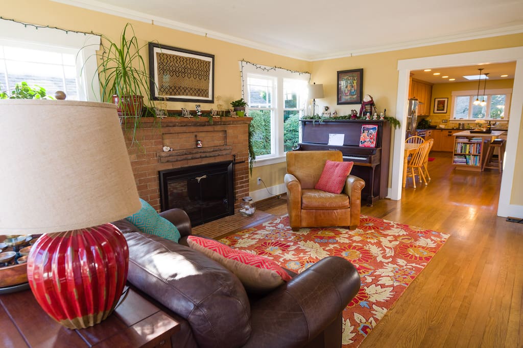 Living room with comfortable leather furniture, stand up piano, and wood burning fireplace.