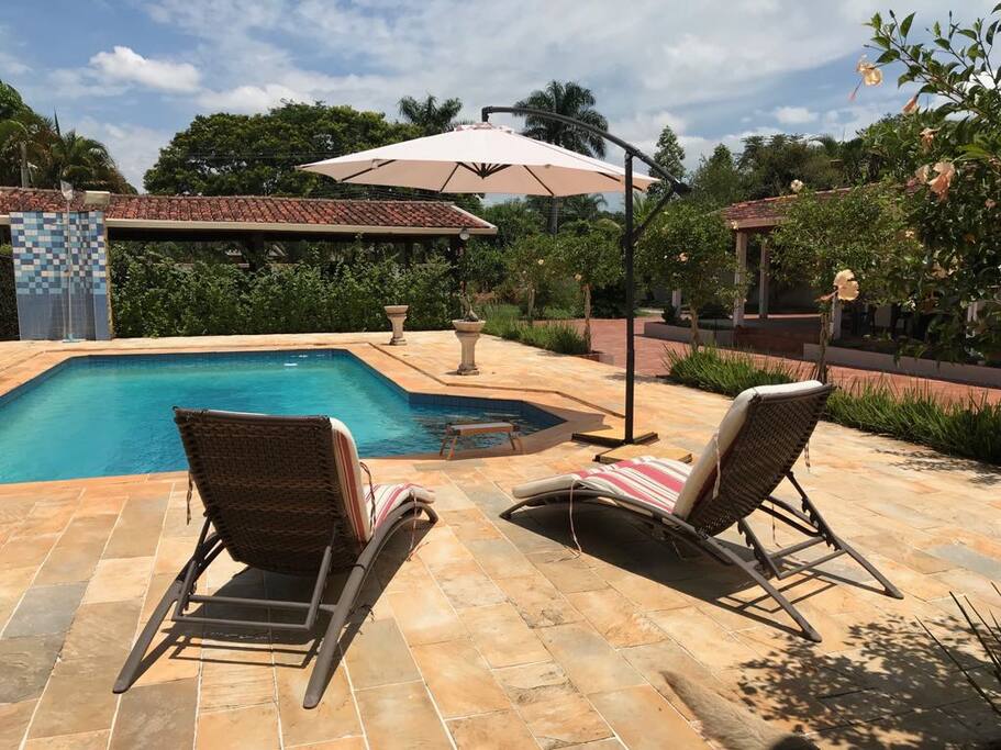 Piscina grande, espreguiçadeiras, guarda sol, ducha.