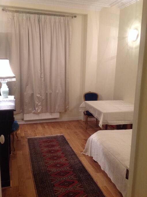 Chambre/Salon avec parquet, cheminée, bibliothèque, canapé clic-clac, table et chaises.
