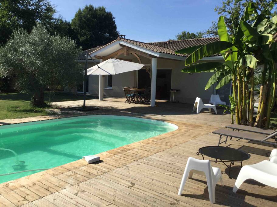 Grande terrasse autour de la piscine, avec coin salon, et espace repas.