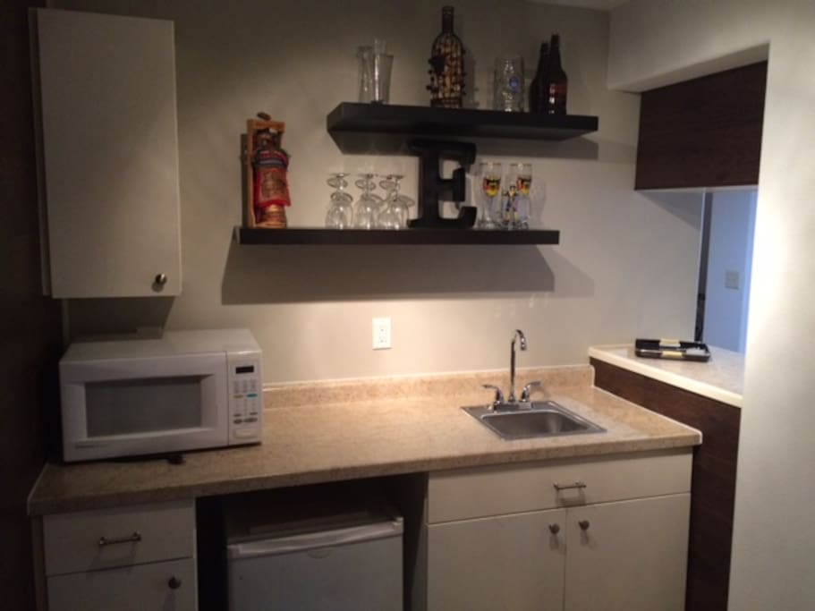 Wet bar area. Small refrigerator, dishes, and microwave. Small "kitchen" area in the basement.