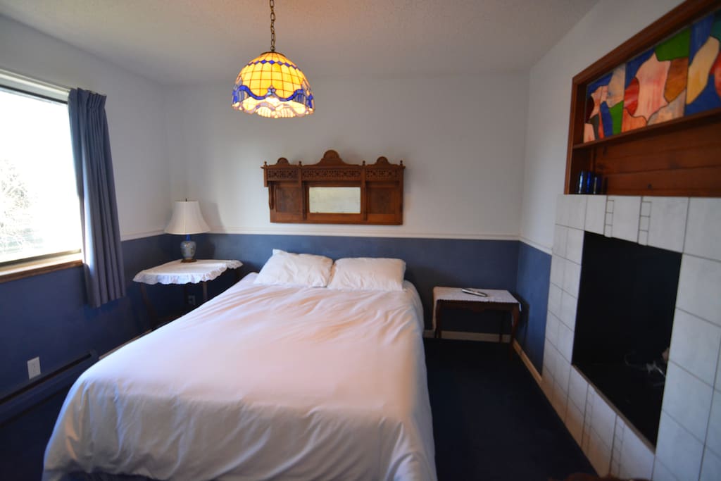 Private bedroom with gas fireplace and a window overlooking the backyard volleyball court.
