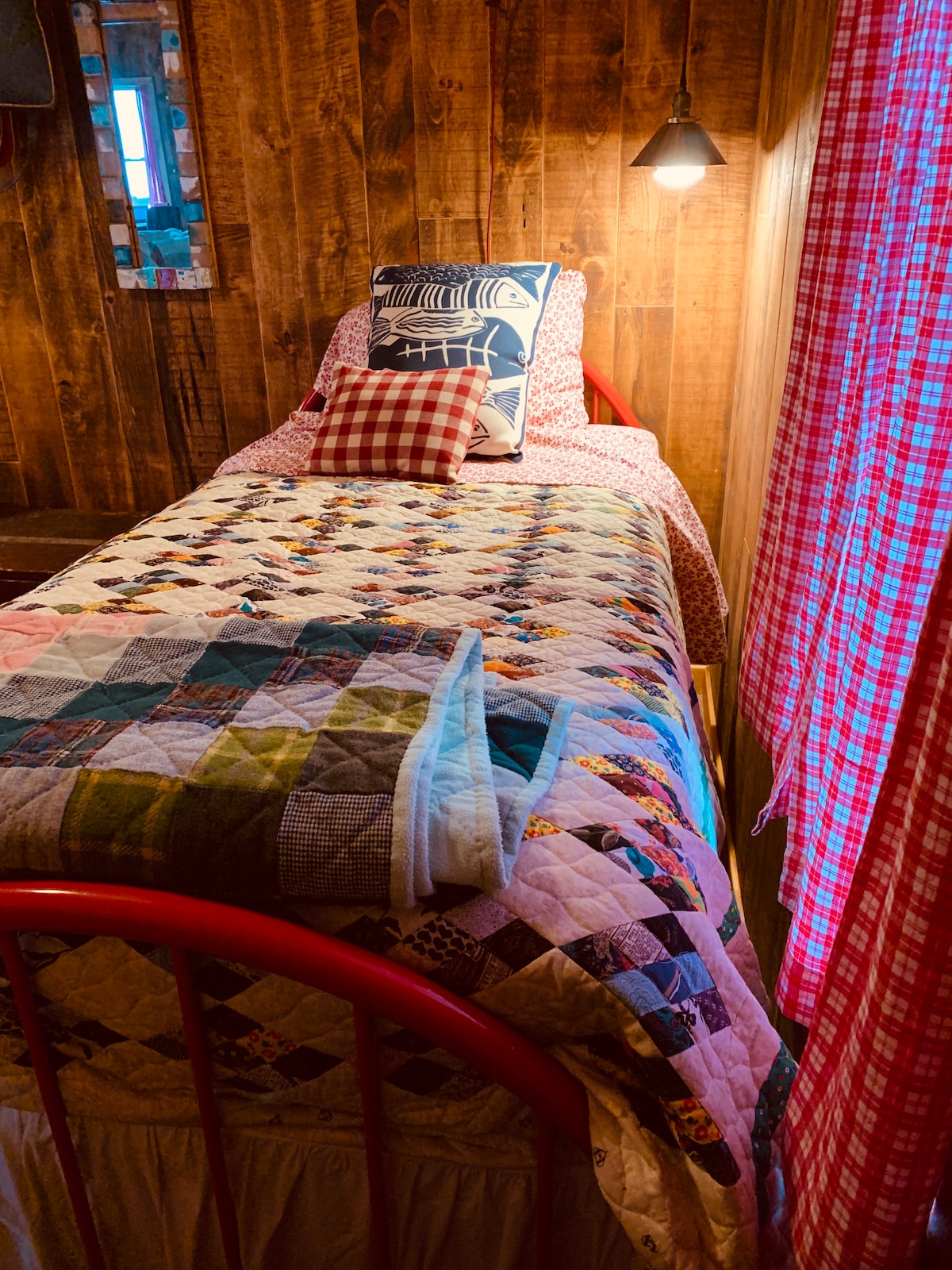 Útulný kútik na čítanie s textúrami domácich prikrývok a rybárskymi suvenírmi.